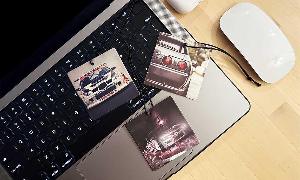 Three JDM car air freshener flat laid on a macbook