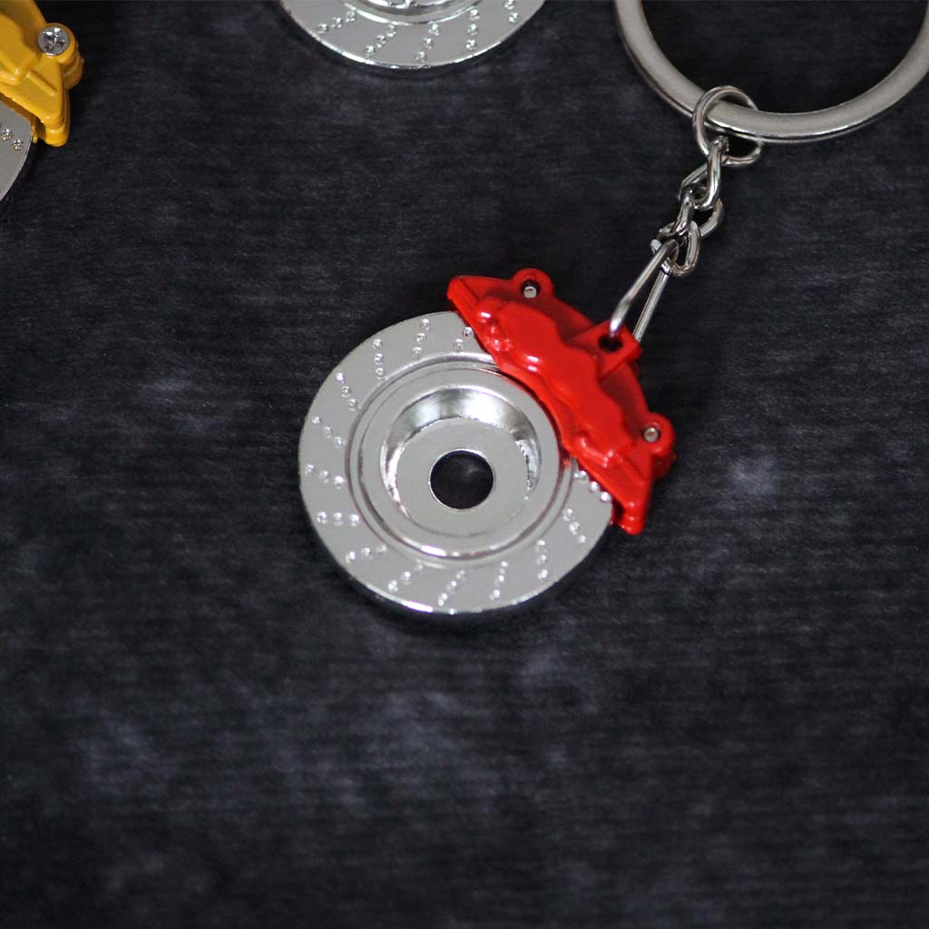 The back of a red brake disc keychain on a dark grey background
