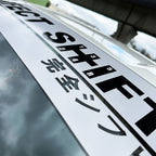 A branded Perfect Shift windshield banner with grey background applied on a Toyota 86 under a bridge