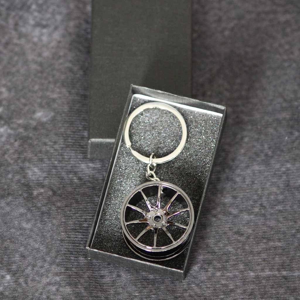 A black wheel keychain in a black gift box on a dark grey background