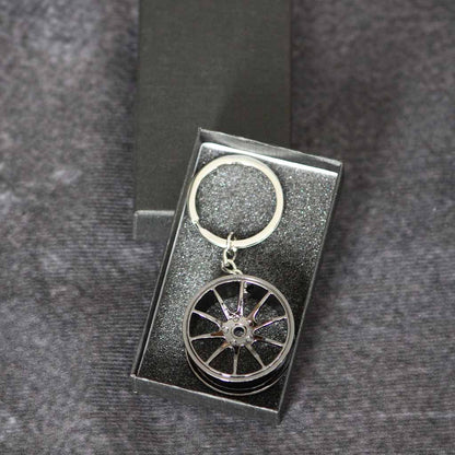 A black wheel keychain in a black gift box on a dark grey background