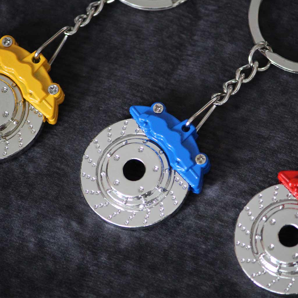 Close-up of a blue brake disc keychain with a yellow and red one on both sides