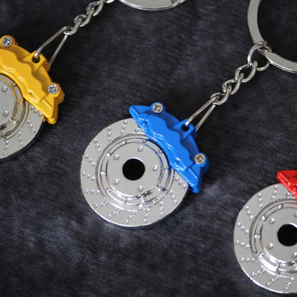 Close-up of a blue brake disc keychain with a yellow and red one on both sides
