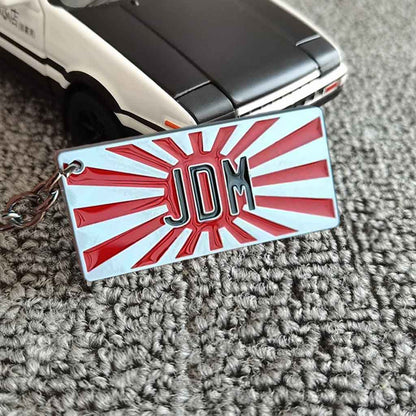 A JDM keychain placed in front of an AE86 car model on carpet