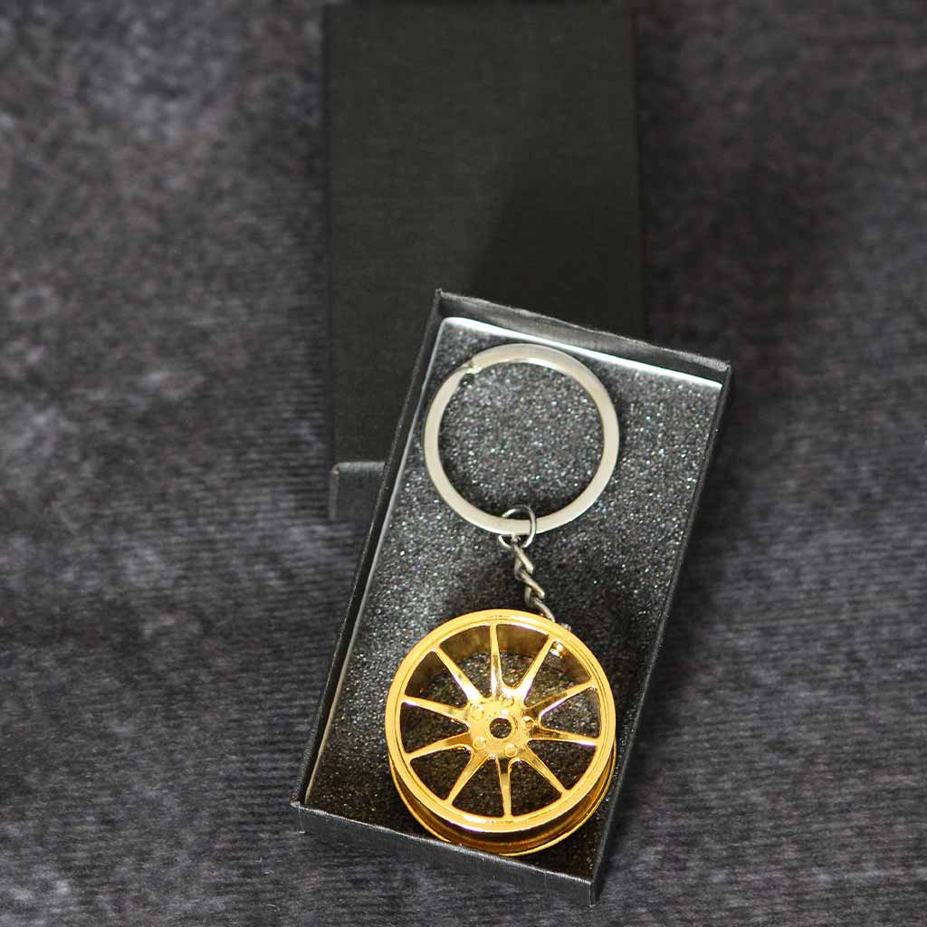 A yellow wheel keychain in a black gift box on a dark grey background