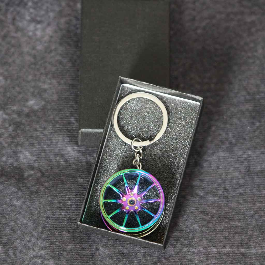 A rainbow wheel keychain in a black gift box on a dark grey background