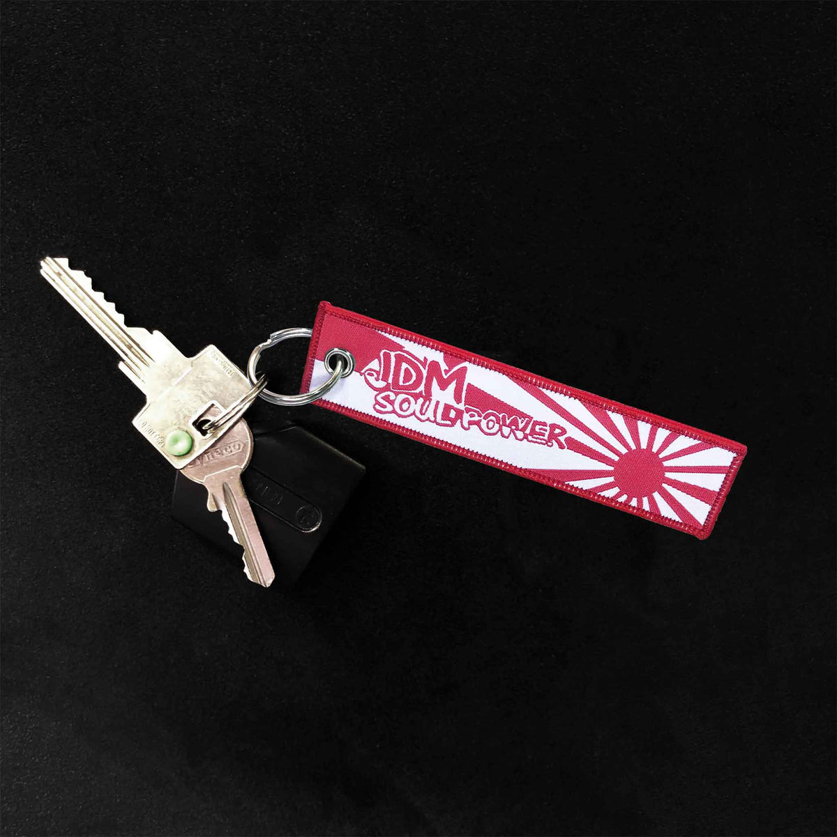 A jet tag holding two door keys on a black background