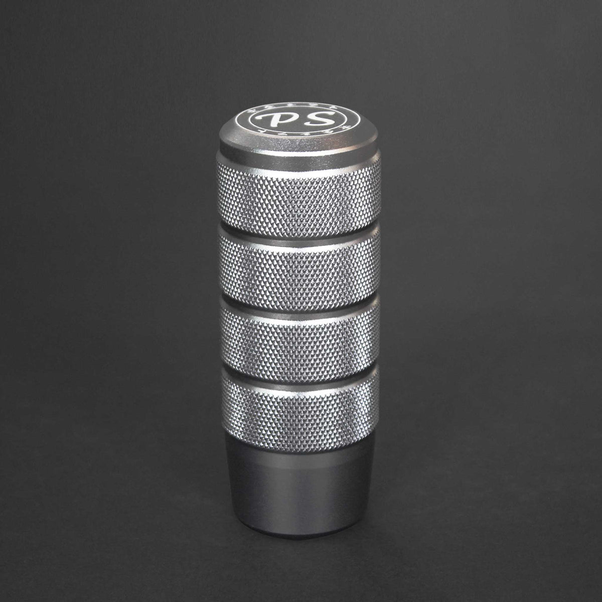 A silver shift knob standing on a black background