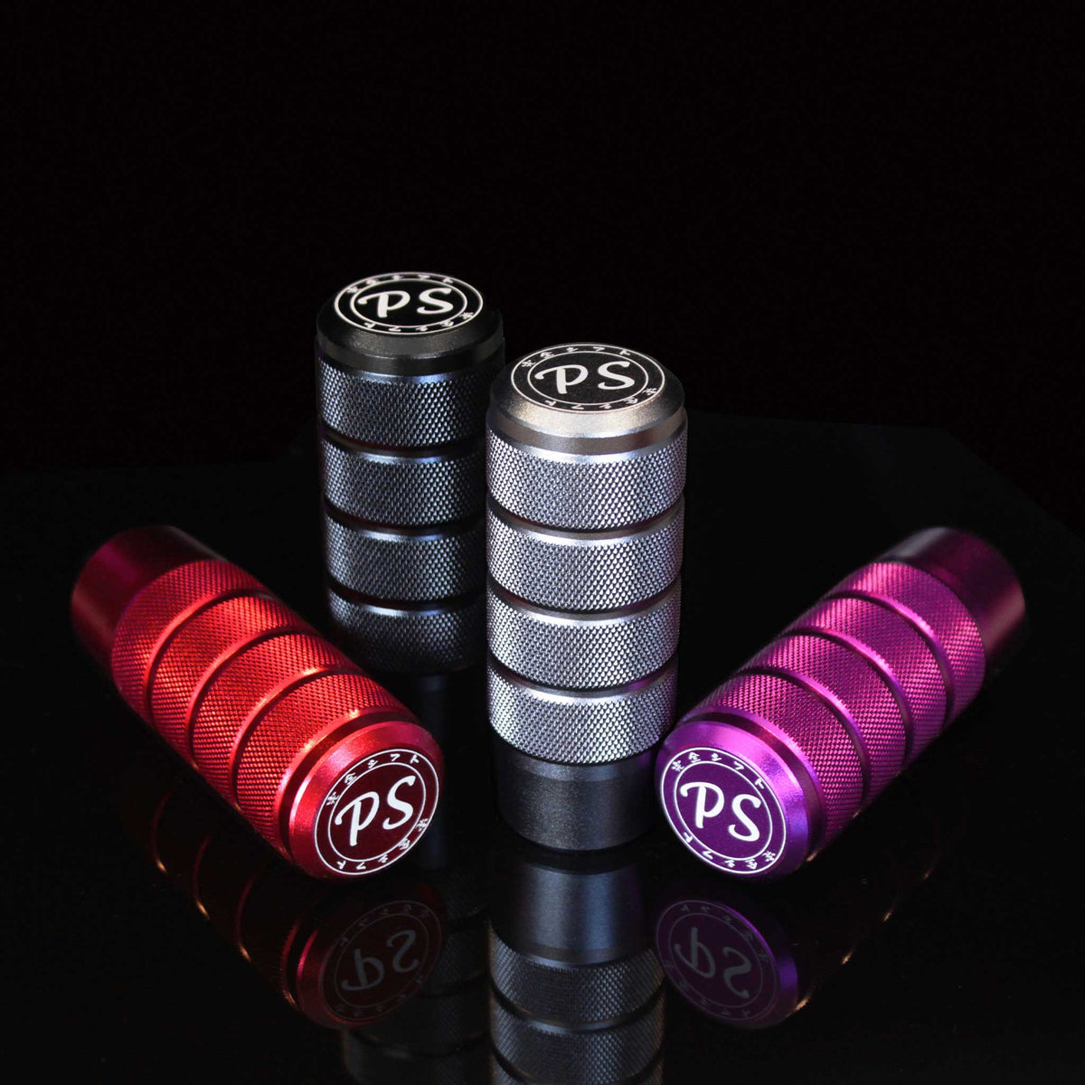 Four shift knobs in different colours aesthetically stand on a mirror