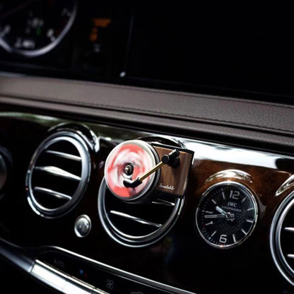 A mini record player air freshener clipped on a car's air-con vents is spinning fast
