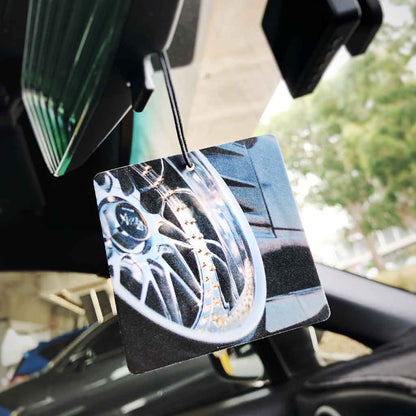 An air freshener featuring a gloss vintage wheel hung in a car