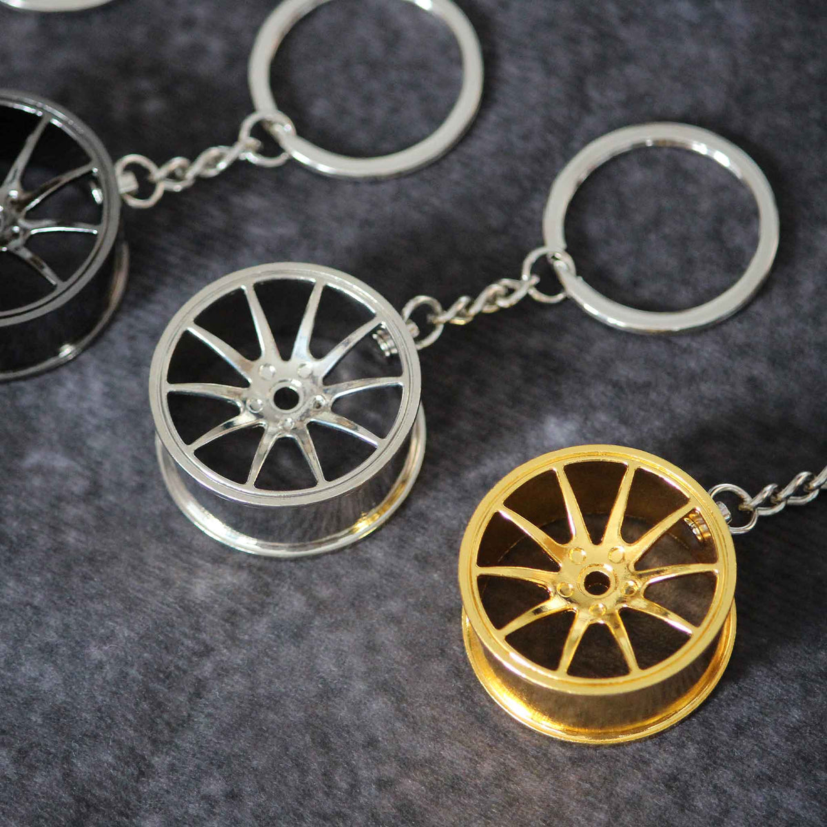 Close-up of a silver and a yellow wheel keychain with a black one on side