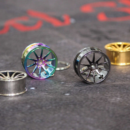 Four wheel keychains placed on a grey floor, two are standing, the other two are laying